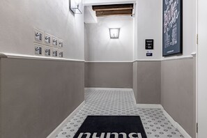 A narrow hallway with patterned flooring, a black rug with the word "PUMA" on it, and a wall-mounted light fixture. - Numa Florence Fiore (Florence)