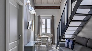 A modern interior with a staircase, a dining area with a table and chairs, and a sofa. - Numa Florence Fiore (Florence)
