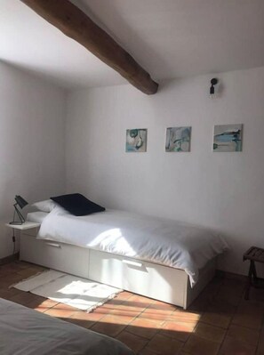 A bedroom with a bed, a nightstand, a lamp, and three wall-mounted paintings.