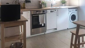 Eine moderne Küche mit weißen Schränken, Edelstahlgeräten und einer Holzbalkendecke.