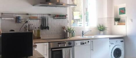Une cuisine moderne avec des armoires blanches, des appareils en acier inoxydable et un plafond en bois.