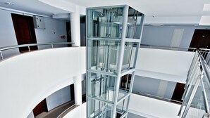 Un interior de varios niveles con barandillas de cristal y un hueco central para el ascensor.