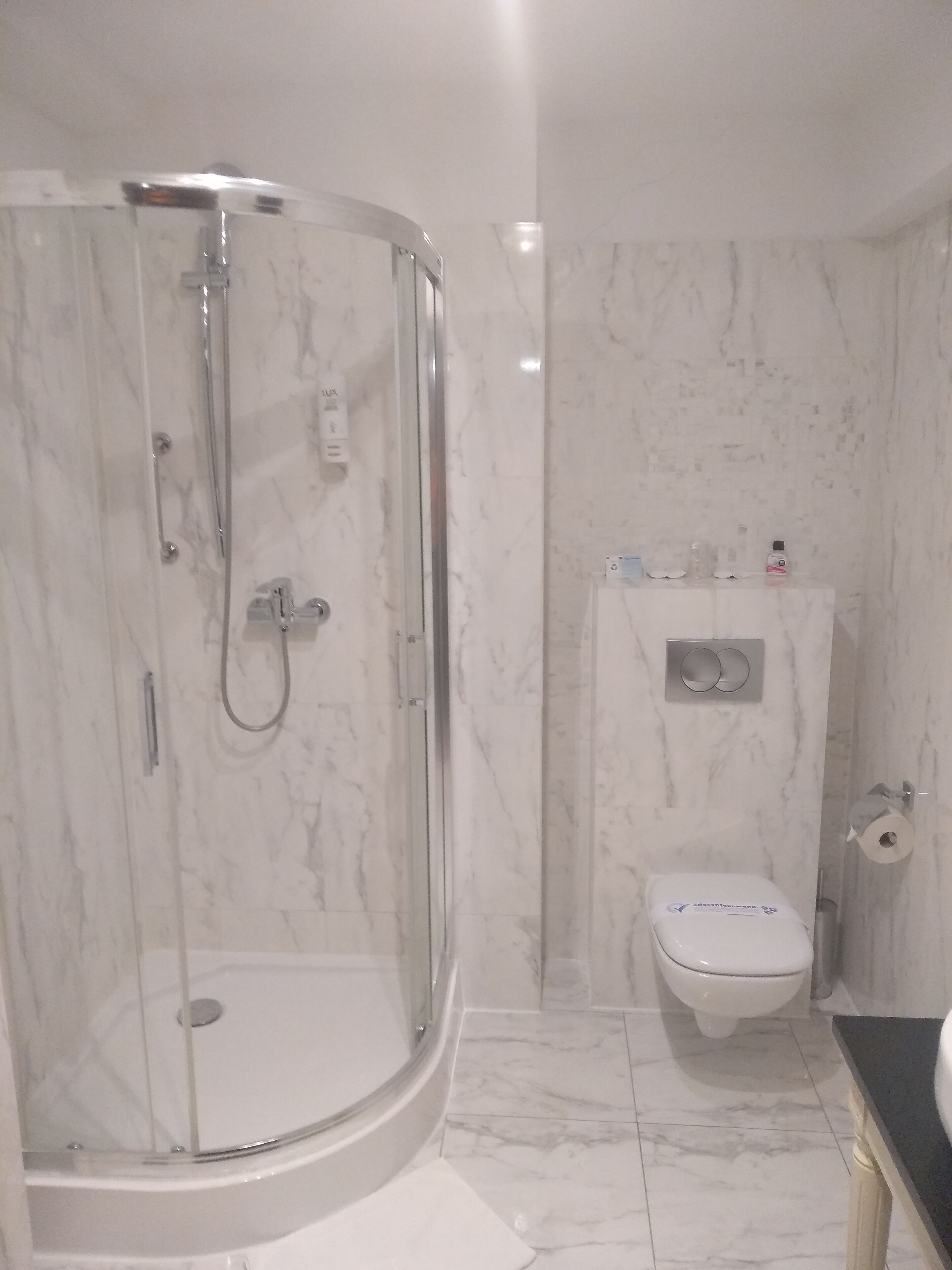 A bathroom with a glass-enclosed shower, a toilet, and a sink.