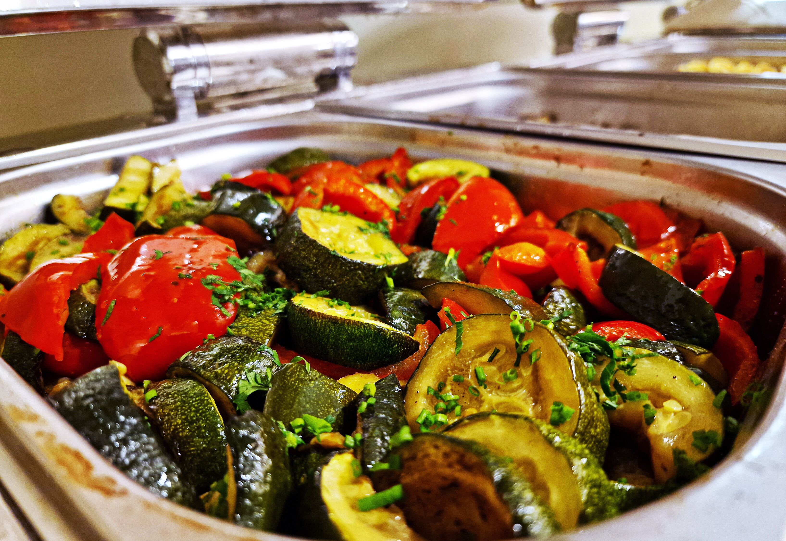 Een buffet met diverse groenten, zoals courgette, tomaten en uien.