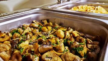 A buffet with various dishes, including a section with mushrooms and potatoes garnished with herbs.