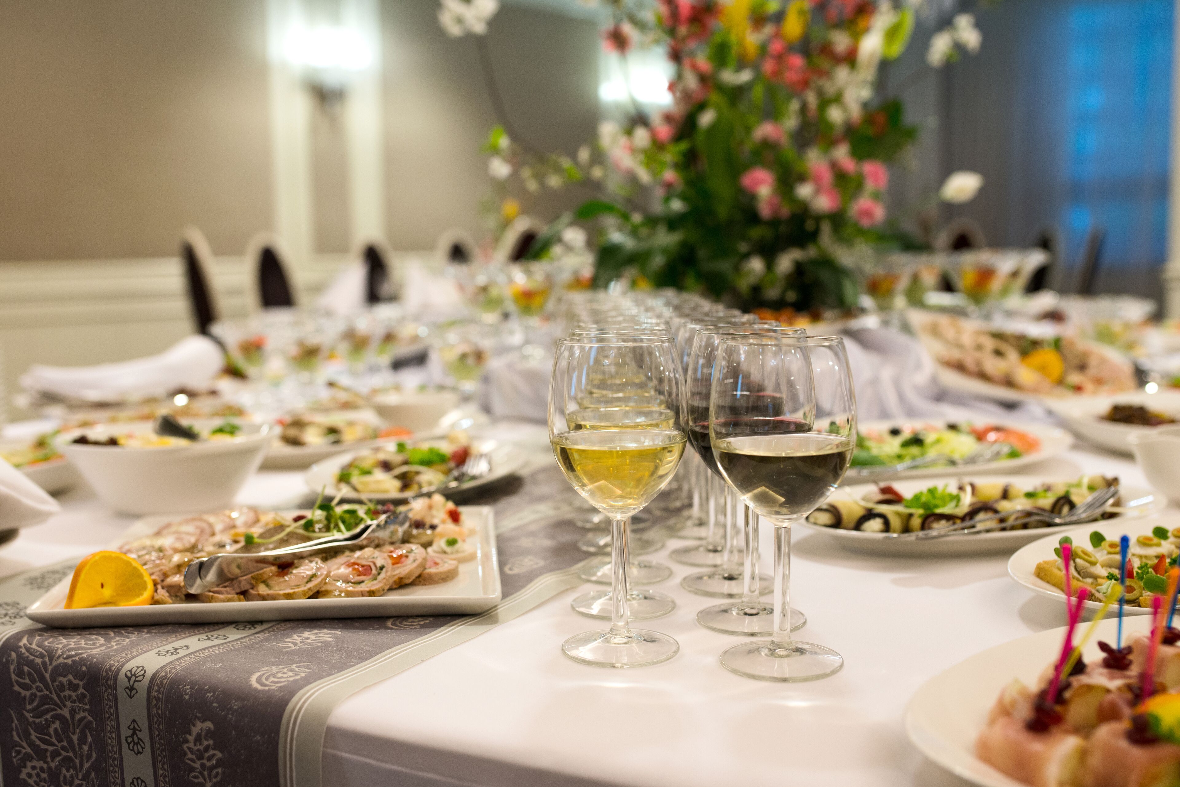 Une table dressée pour un dîner formel, avec de nombreuses assiettes remplies de nourriture, des verres à vin et un centre de table floral.