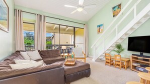 A living room with a sofa, TV stand, and a staircase. - Hale Nani ~ Beautiful Hawaiian Home (Kawela Bay)