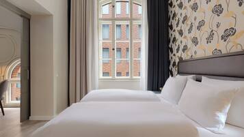 Ein Hotelzimmer mit einem großen Bett, Blick auf ein Backsteingebäude und einer Wand mit Muster.