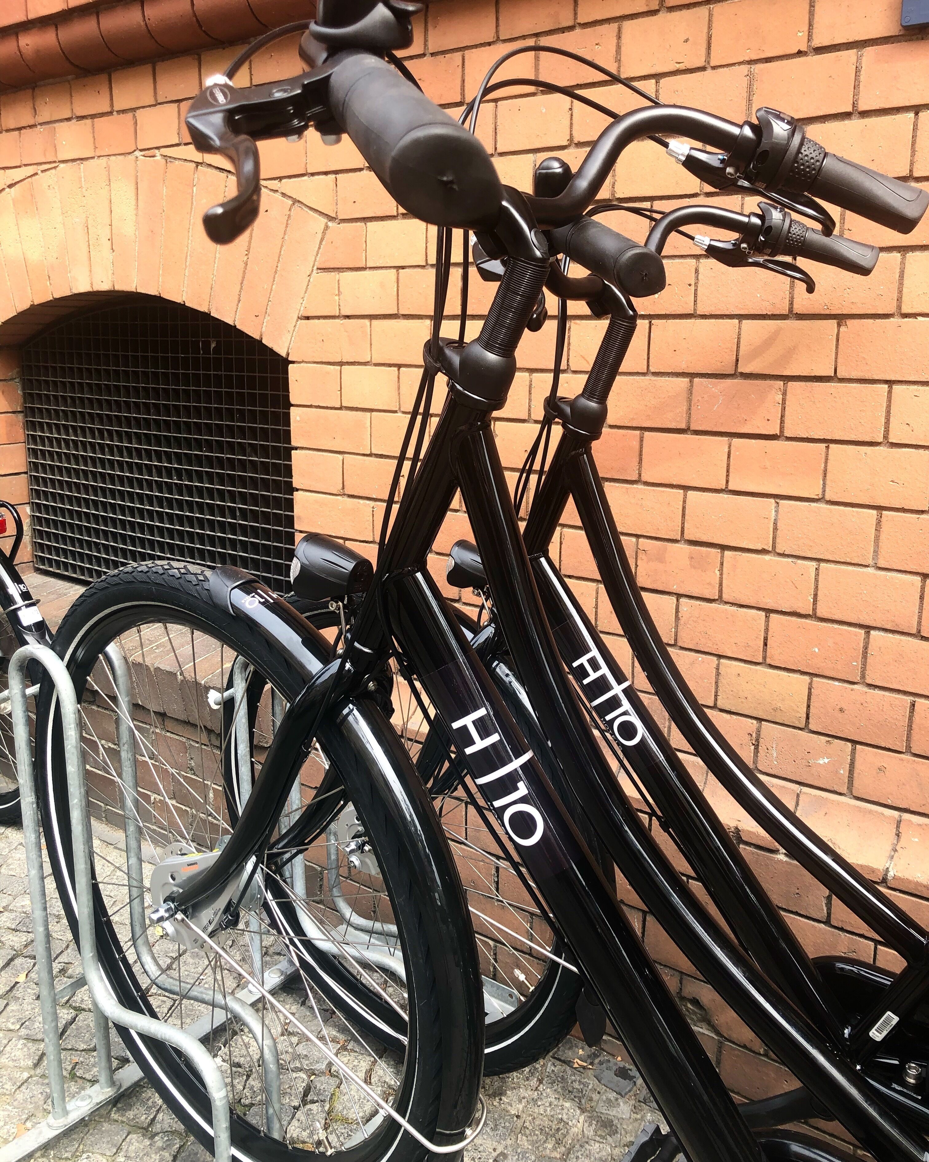 A black bicycle with the brand name "Hilo" on the frame, leaning against a metal bike rack.