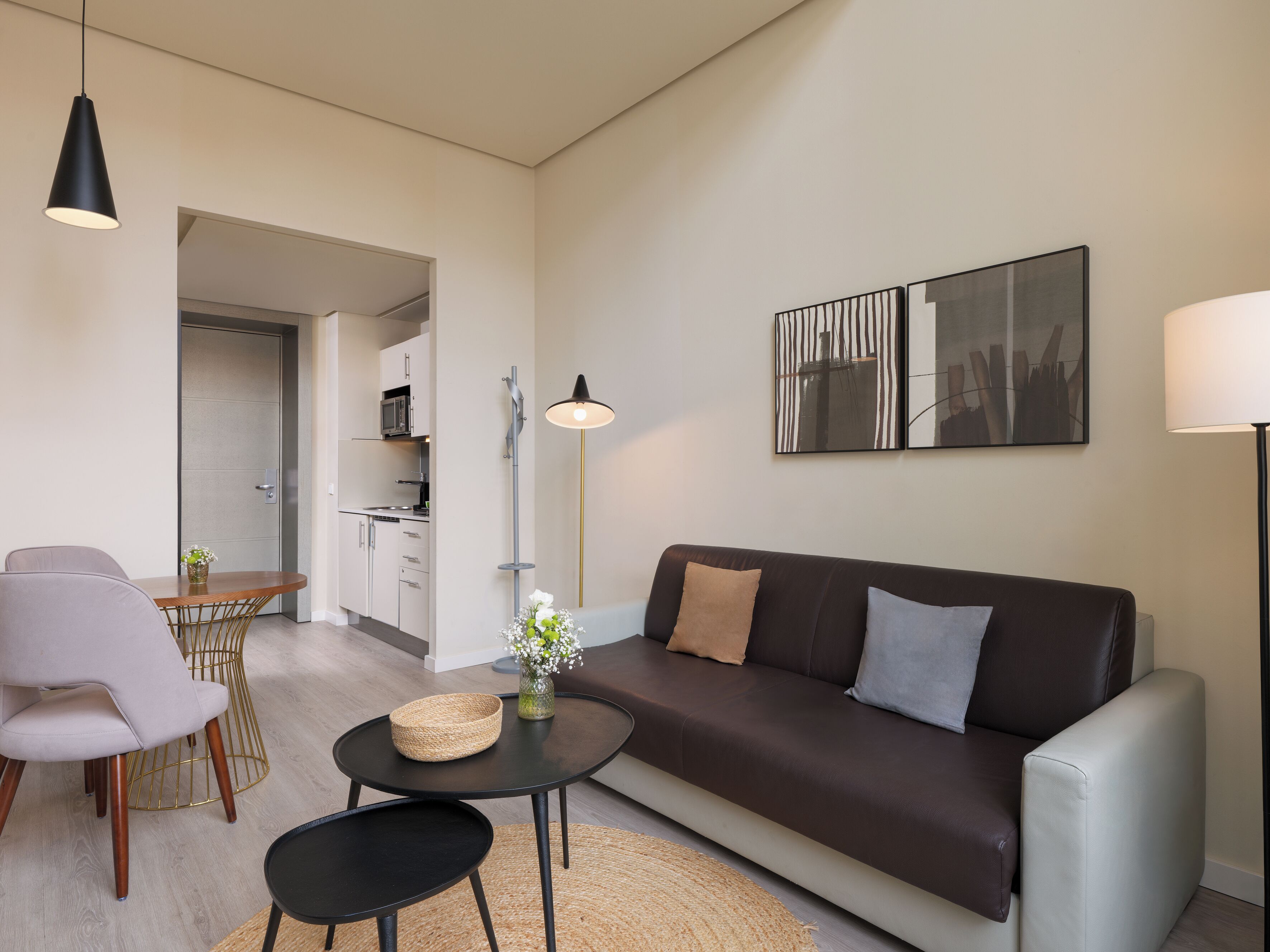 Una sala moderna con un sofá, dos sillones, una mesa de centro, una lámpara de pie y un comedor con mesa y sillas.
