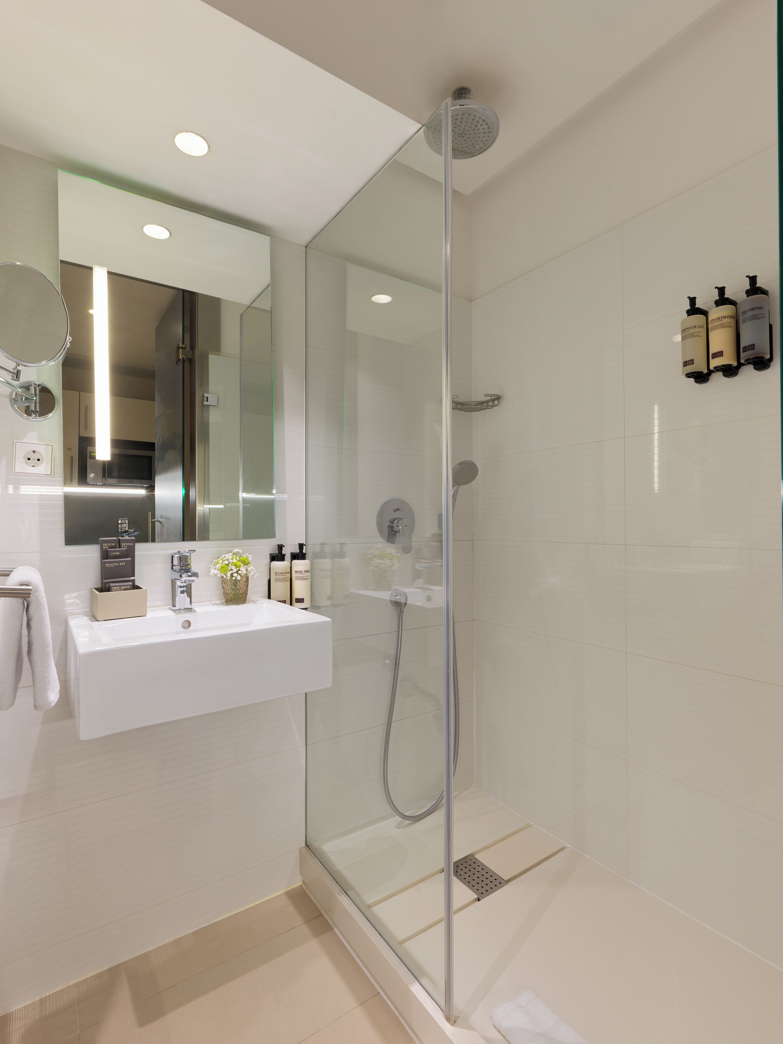 A modern bathroom with a glass-enclosed shower, a white sink, and a mirror above it.