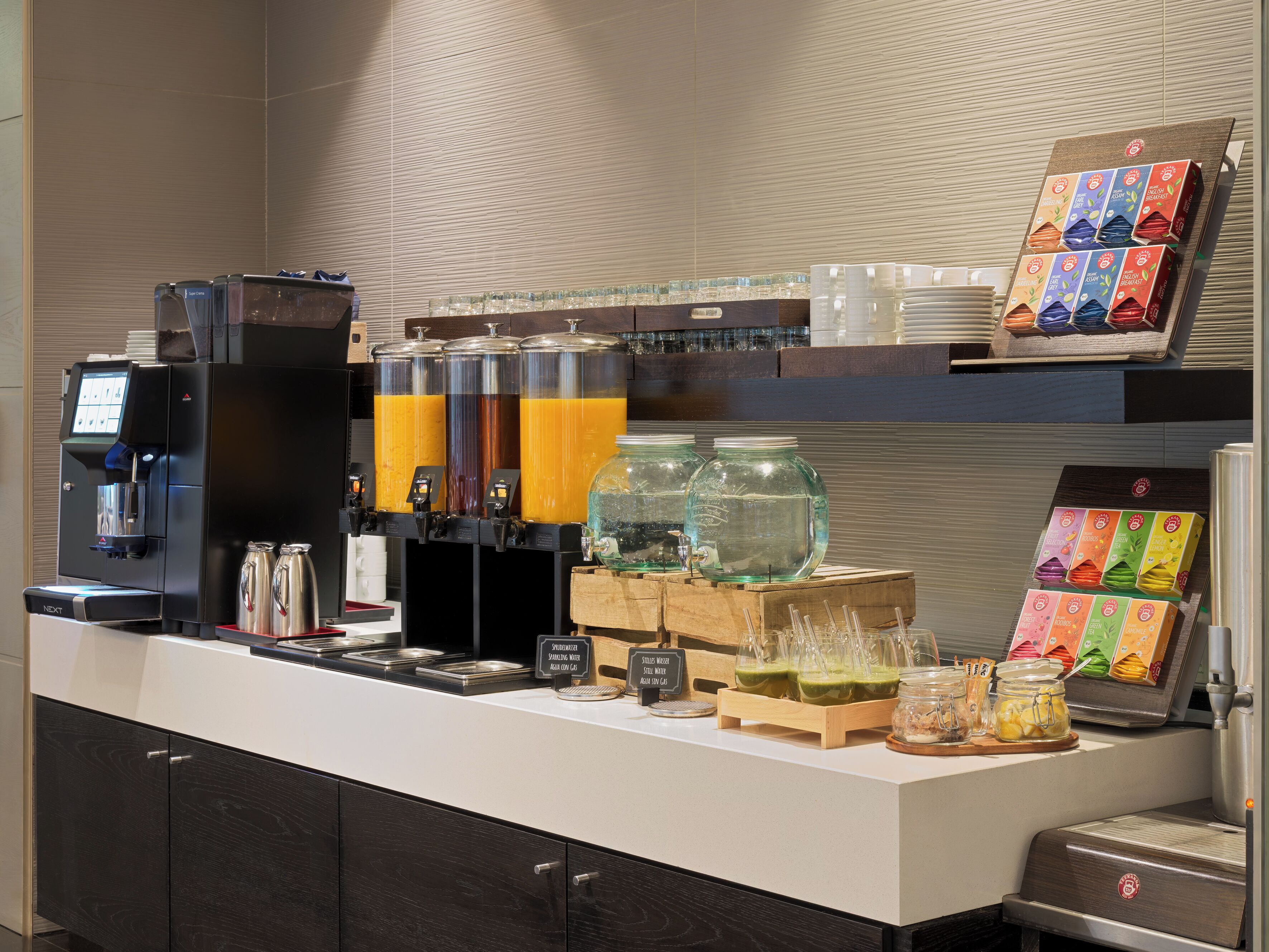 Een zelfbedieningsgedeelte met verschillende drankdispensers, een koffiemachine en een assortiment aan etenswaren.