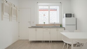 Une cuisine moderne avec des armoires blanches, un four à micro-ondes encastré et une fenêtre offrant une vue géométrique.