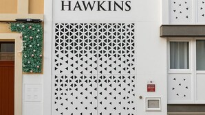 Une façade d’immeuble ornée d’un motif géométrique et sur laquelle le nom « HAWKINS » est clairement visible.