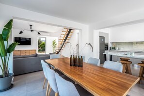 A modern kitchen with a built-in oven, a dining area with a wooden table and chairs, and a staircase leading to an upper level.