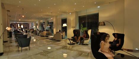 A spacious lobby with a polished marble floor, modern seating areas, and ambient lighting.