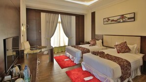 Ein Hotelzimmer mit zwei Betten, einem Fernseher, einem Schreibtisch und einem roten Teppich.