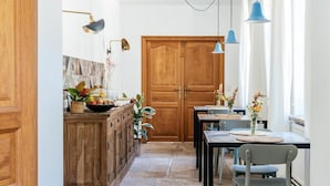 A kitchen with wooden cabinets, a stone floor, and a dining area with a table and chairs. - Villa Parkbos (De Pinte)