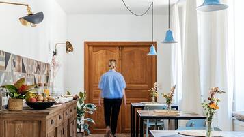 A kitchen with a wooden cabinet, a dining table with chairs, and hanging pendant lights.