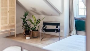 A bedroom with a sloped ceiling, a bed, a bedside table, a wardrobe, and potted plants. - Villa Parkbos (De Pinte)