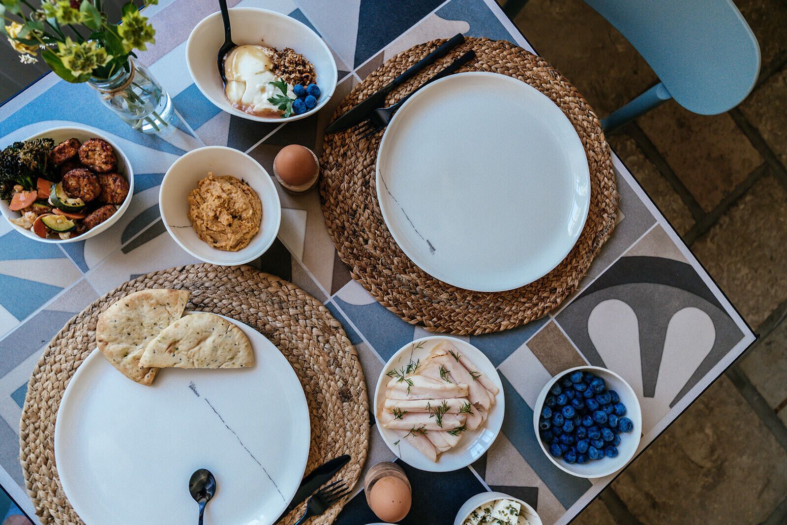 Ein Tisch reichhaltig gedeckt mit verschiedenen Speisen, darunter Brot, Eier und eine Schüssel Blaubeeren.