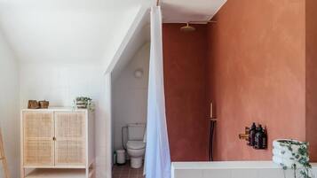 Une salle de bain avec une douche, des toilettes et un meuble sur lequel est posée une plante.