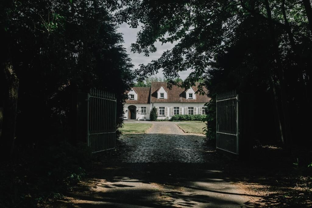 A pathway leading to a traditional house with a tiled roof and white walls.