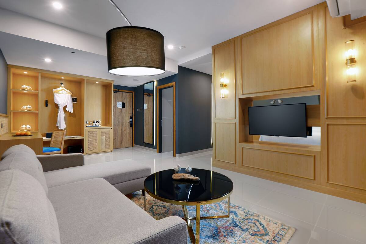 Een moderne woonkamer met een bank, een ronde salontafel en een televisie bevestigd aan een houten wand.