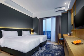 A modern hotel room with a large bed, a desk with a chair, a flat-screen TV, and a balcony with curtains.