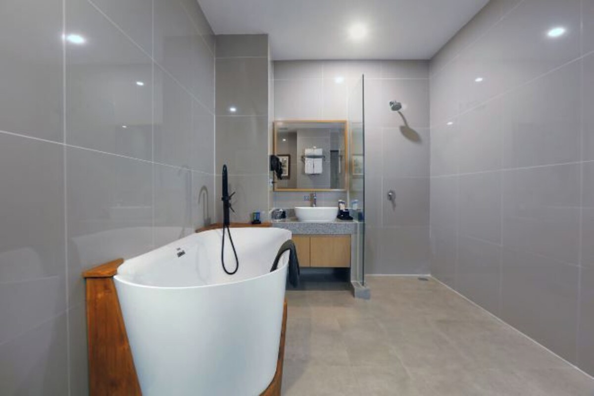 A modern bathroom with a freestanding bathtub, a glass-enclosed shower, and a vanity with a mirror.