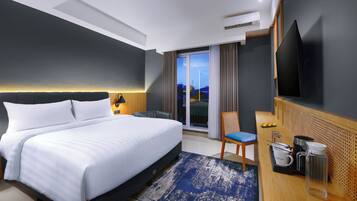 A modern hotel room with a large bed, a desk with a chair, a flat-screen TV, and a view of the outdoors.