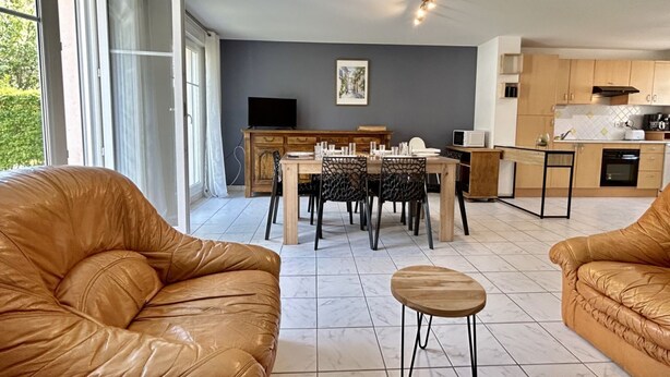 Un salon moderne avec des canapés en cuir, une table à manger et un coin cuisine doté de meubles en bois et d’un four à micro-ondes.