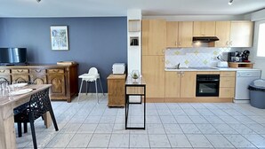 Une cuisine compacte avec des meubles en bois, une table à manger, un téléviseur et un dosseret carrelé.