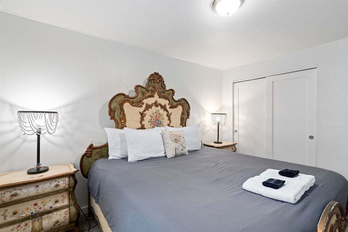 A bedroom with a large bed, two bedside tables, a dresser, and a door.