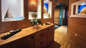Un intérieur en bois avec un comptoir d’accueil, une plante en pot et des œuvres d’art accrochées aux murs.