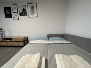 A modern bedroom with a bed, pillows, a wooden side table, and wall art.