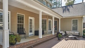 Eine überdachte Veranda mit Holzboden, Gartenmöbeln und Blumentöpfen.