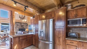 Eine moderne Küche mit Holzausstattung, Edelstahlgeräten und einem Kamin aus Stein.