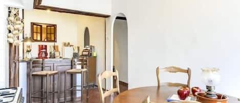 Un comedor con una mesa redonda de madera, sillas y una cocina al fondo.