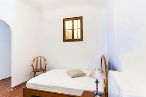 A single bed with a wooden headboard, a small window, a chair, and a bedside table with a lamp. - Retro-vintage loft style in the heart of the Old Port (Marseille)