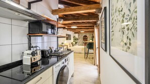 Une cuisine compacte équipée d’un four à micro-ondes, d’un grille-pain et d’un lave-linge, qui donne sur un coin repas avec une table et des chaises.