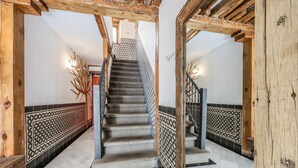Un escalier dont le sol est recouvert d’un motif à carreaux, avec des poutres en bois et des carreaux muraux décoratifs.