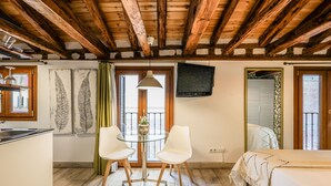 A room with a wooden ceiling, a bed, a TV, a dining table with chairs, and a window with curtains. - Beautiful Renovated Loft in the center 010  (Madrid)