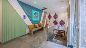 A modern hotel lobby with a teal and green color scheme, a neon sign reading "AMAZING places", a wheelchair-accessible sign, and a seating area with a bench and cushions. - Blasco de Garay, double room with gym 118 (Madrid)