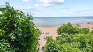 A beach with a staircase leading down to the sand, surrounded by greenery.