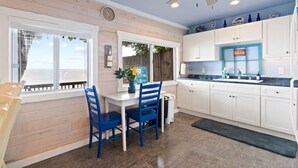 A kitchen with white cabinets, a blue ceiling fan, and a window overlooking a wooden deck.