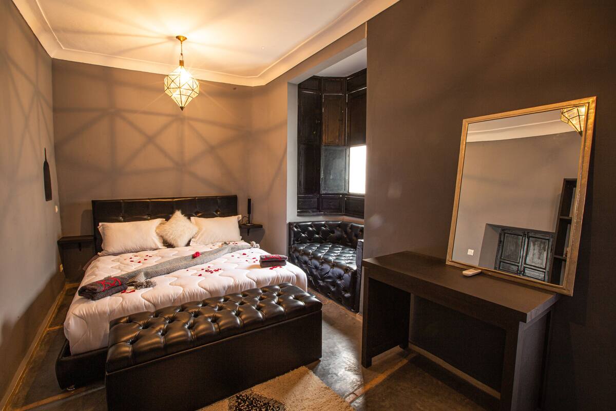 Un dormitorio con una cama grande, un rincón de descanso, un aparador y un espejo.