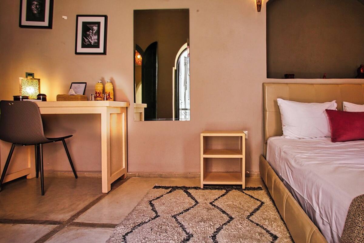 Una habitación de hotel con una cama, un escritorio, una silla y una mesita.