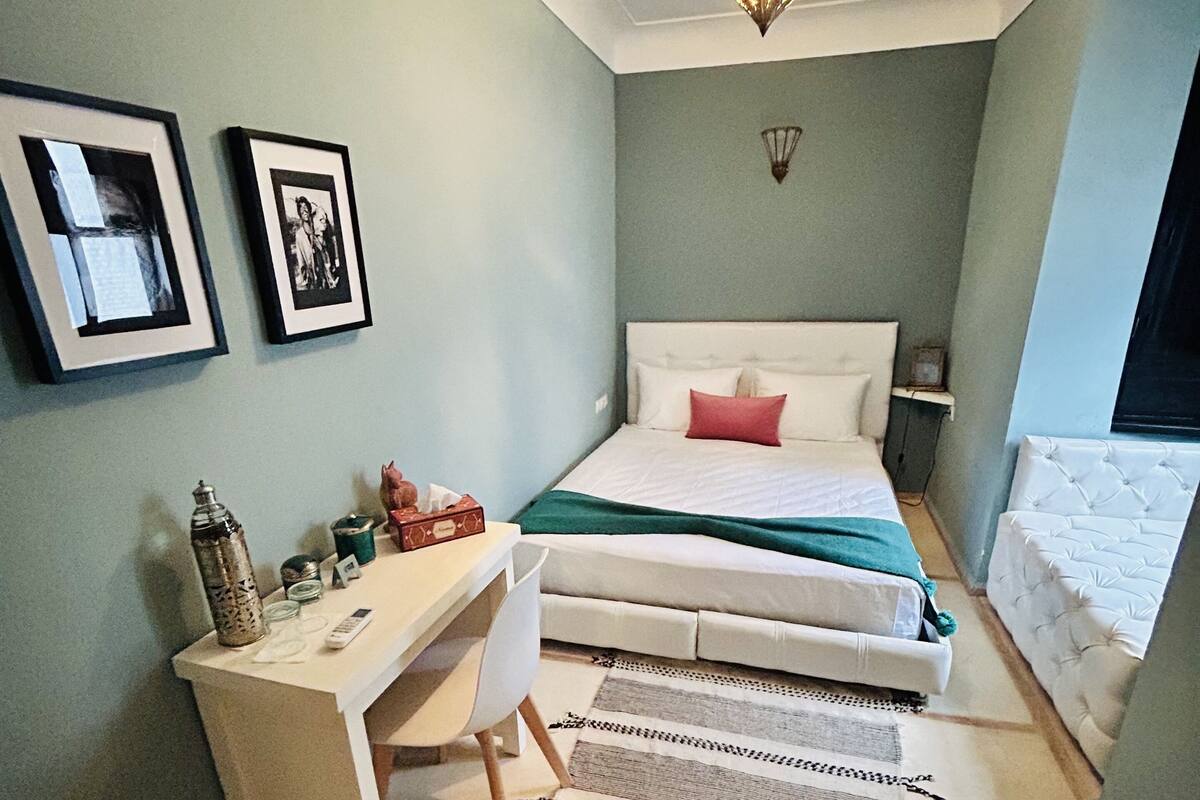 Un dormitorio con cama, escritorio, silla y lámpara colgante.
