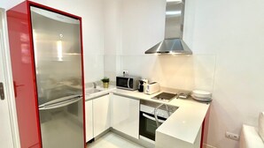 A compact kitchen with a refrigerator, microwave, toaster, and oven. - Design apartment in Plaza Mayor 2 I (Madrid)